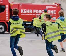 Kehrmaschine und Radlader fahren bei Kinderuni